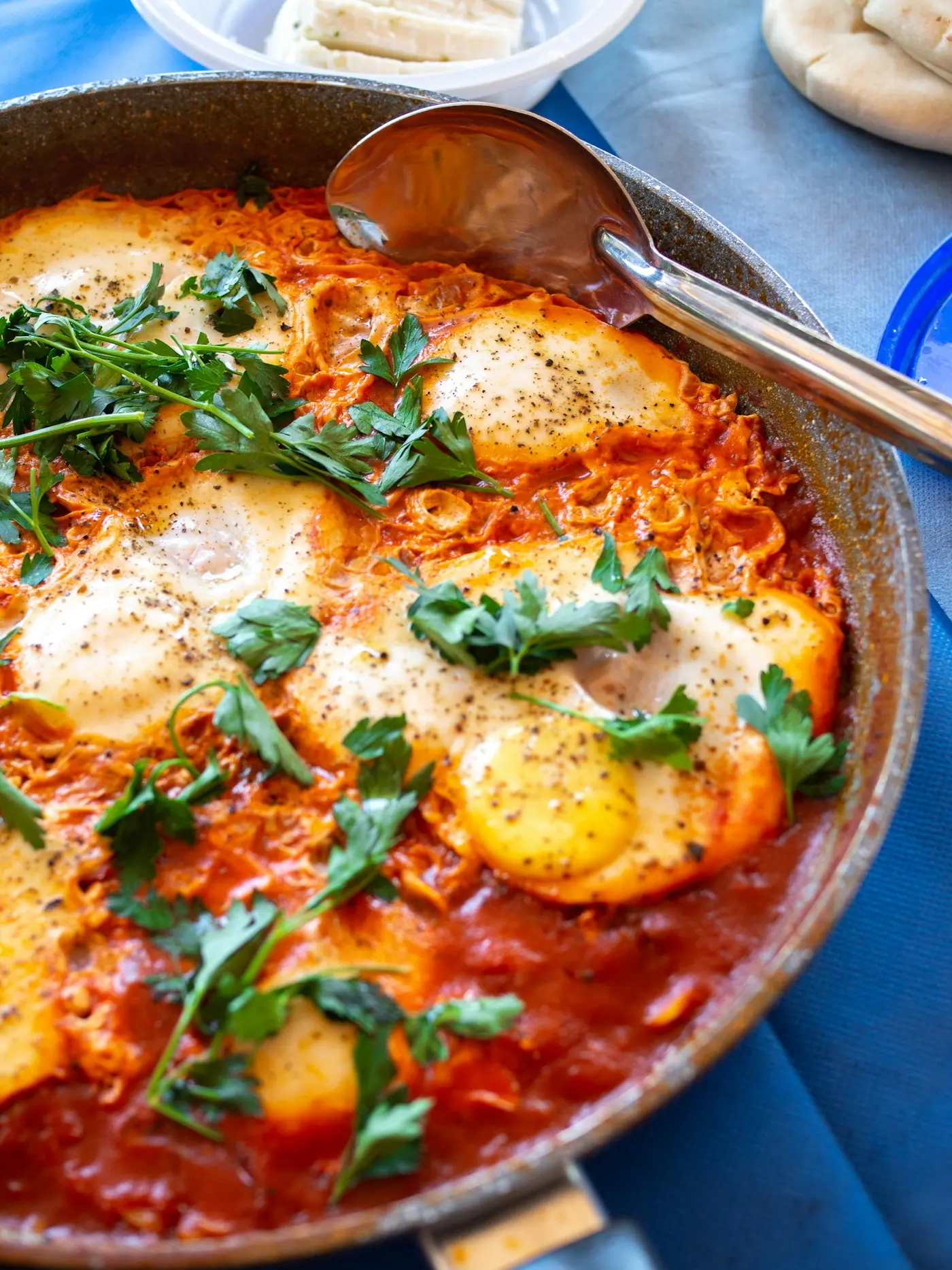 Shakshuka with eggs poached in a spiced tomato and pepper sauce in a skillet